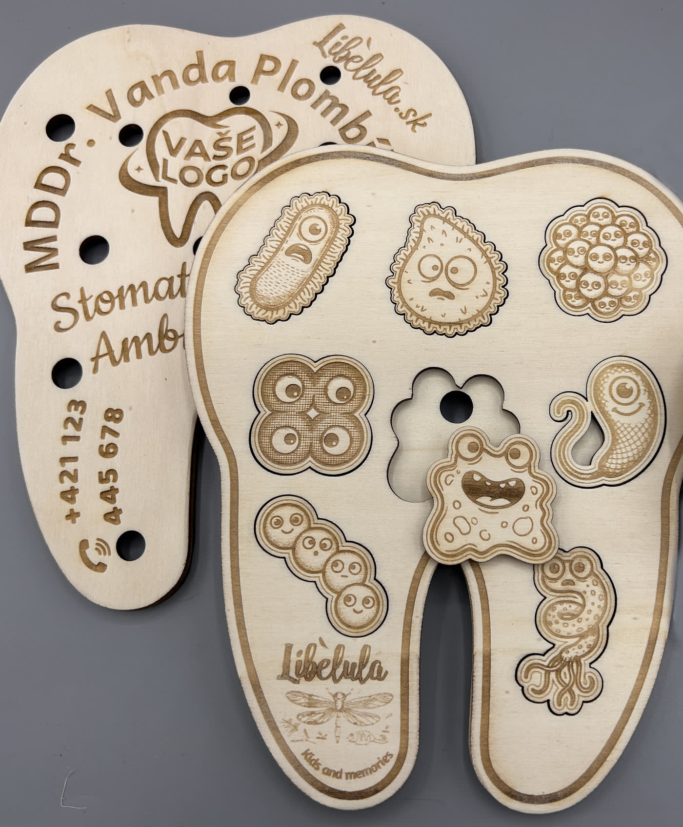 Tooth-shaped wooden inset puzzle engraved with a dental practice's name, address and telephone number