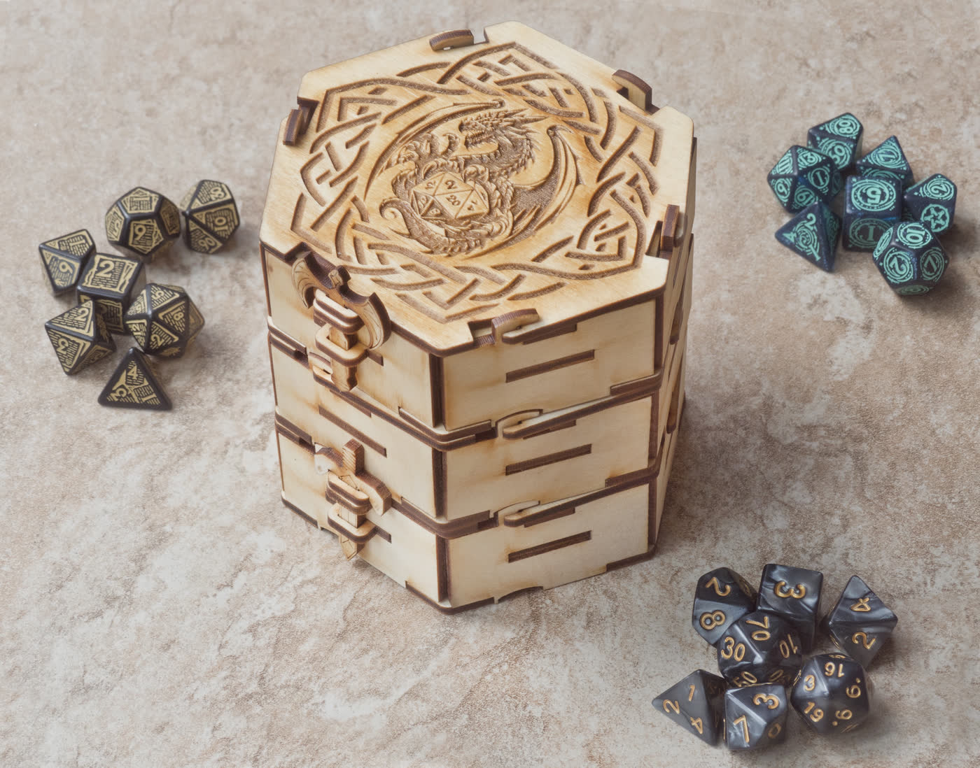 Three hexagonal dice boxes stacked into a tower beside loose polyhedral dice