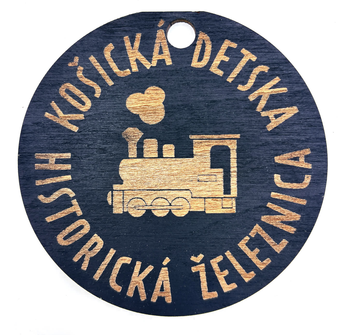 Round wooden tag engraved with a steam locomotive and the name of the Košice children's historical railway