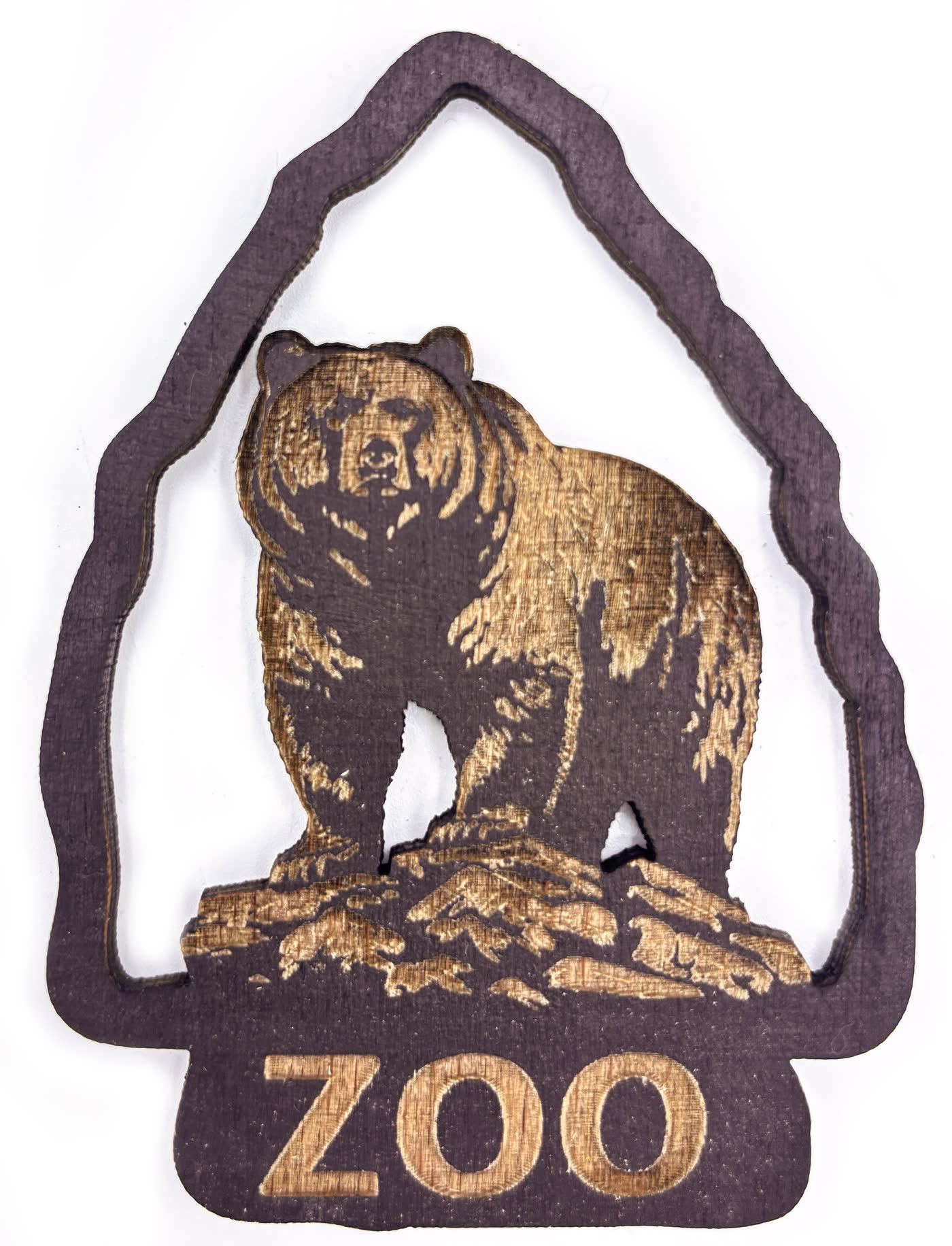 Wooden souvenir medallion with a bear engraved in relief and the word ZOO beneath it